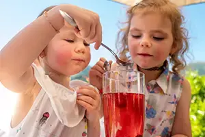 2 Mädchen trinken im Garten einen Obstsaft