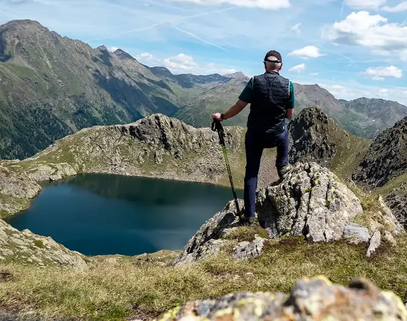 Wanderer steht oberhalb eines Bergsees und schaut auf das Bergpanorama des Villgratentals