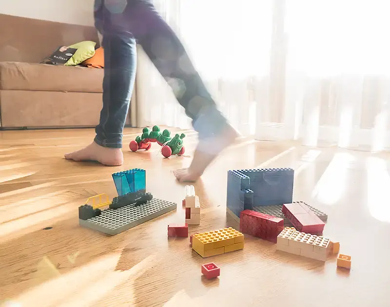 Kinderspielsachen liegen am Boden, Licht fällt durch den Vorhang herein